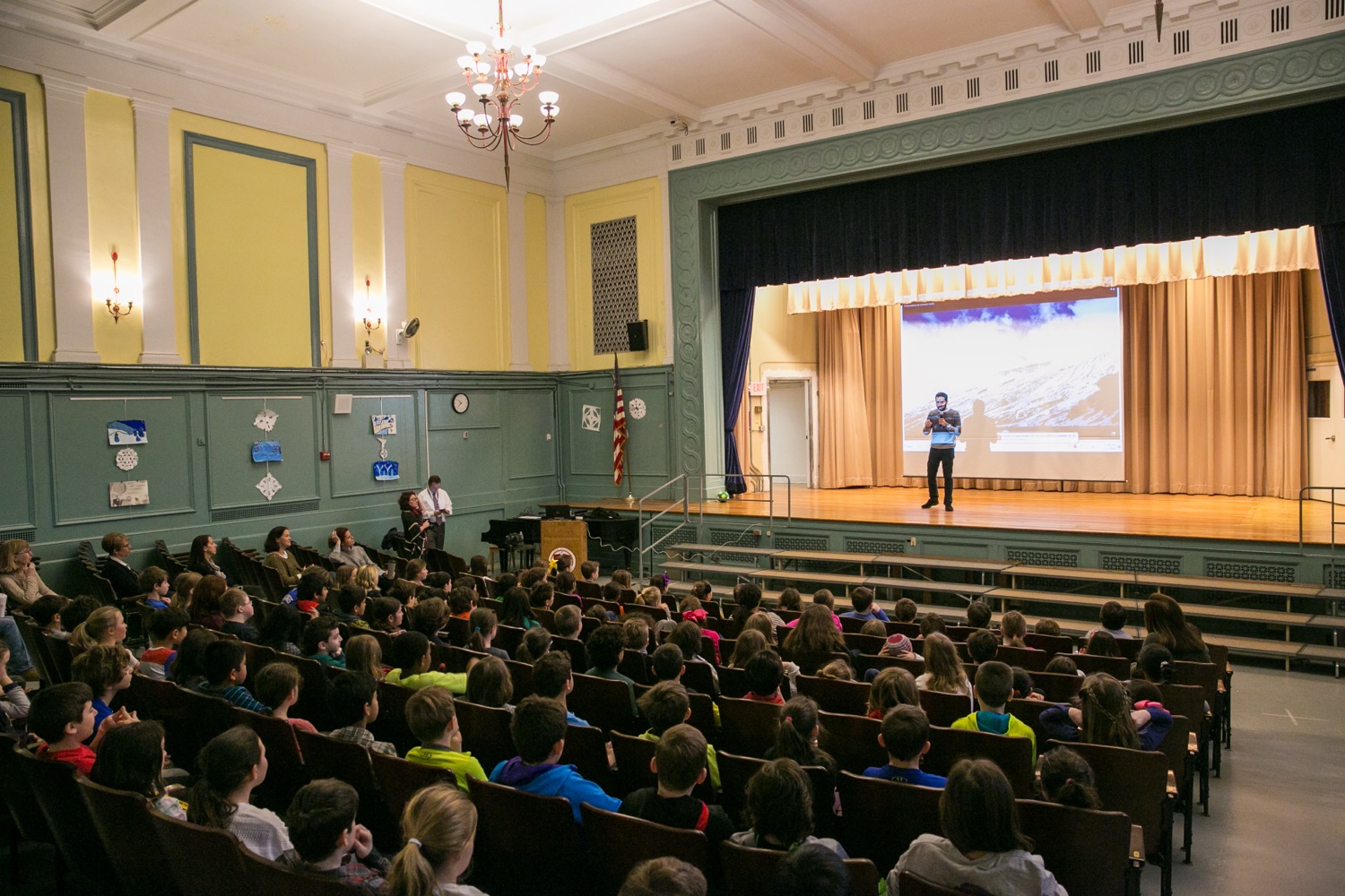 Back of a man at a concert. Hes wearing a beanie hat and a baggy denim jacket with studs. Photo with a purple hue